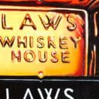Close-up of Monica Marquez Gatica's LAWS Fluid Whiskey painting, revealing intricate oil details of the whiskey bottle.