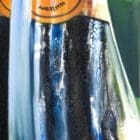 Painting detail by Monica Marquez Gatica featuring the neck of a Veuve Clicquot bottle with a mountainous background.